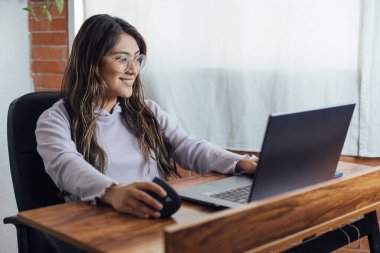 Mexican woman with home office works happy in front of computer