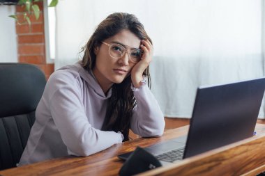 Mexican woman with home office, has frustration face in front of the computer