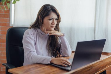 Mexican woman with home office, has frustration face in front of the computer