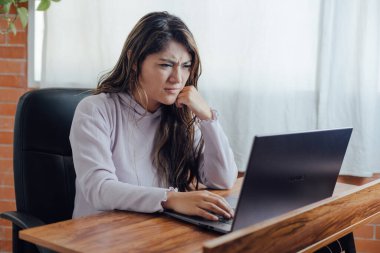 Mexican woman with home office, has frustration face in front of the computer