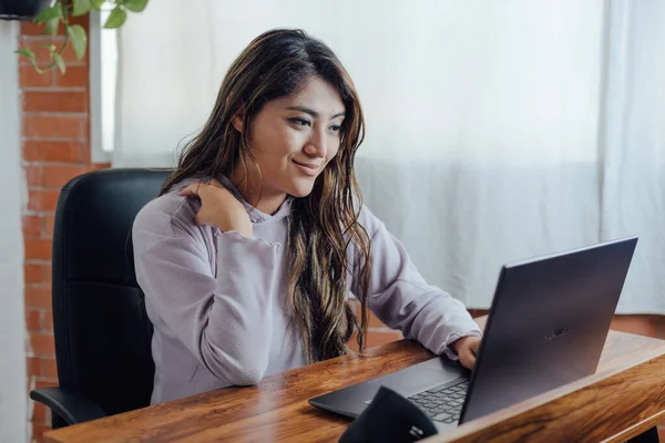 Mexican woman with home office works happy in front of computer