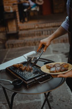 Izgara mutfağı. Şef füme domuz pirzolası kesmek için bıçak kullanır..