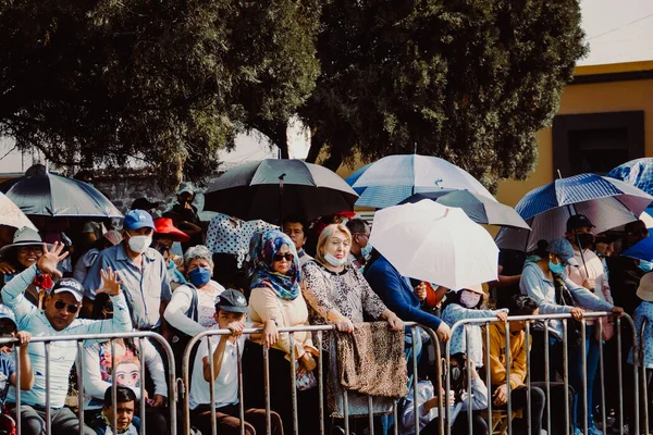 Metal çitlerin arkasındaki izleyiciler 5 Mayıs geçit töreninin başlamasını bekliyorlar.