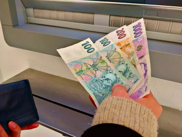 Bir kişi ATM 'den dört Çek banknotunu çekiyor. Kadın ya da erkek, sol elinde cüzdan tutuyor..