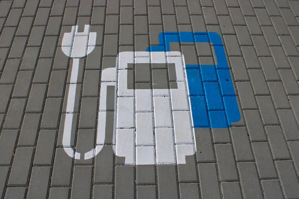 Symbol of car electric power charger drawn on the parking place using white and blue colors.