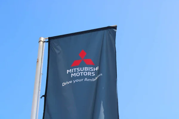 Ceske Budejovice, Çek Cumhuriyeti - 26 Mart 2022: Mitsubishi Motors 'un logosu, arkasında temiz mavi gökyüzü olan bir otomobil satıcısının çatısında şirketin adı yazılı..