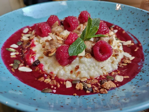 Müsli kahvaltısı. Ahududu reçeli, ahududu, nane ve tohumla birlikte. Yemekler güzel mavi dekoratif tabakta servis edilir..