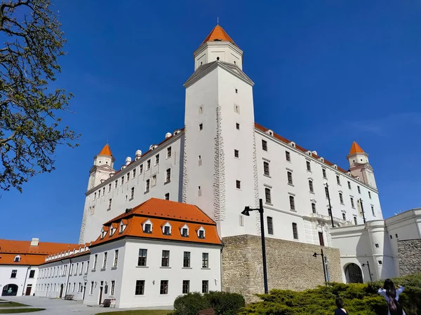 Bratislava, Slovakya - 13 Nisan 2022: Arkadaki güzel mavi gökyüzü ile köşeden görülen Bratislava kalesi.