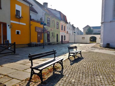 Ceske Budejovice, Çek Cumhuriyeti - 31 Ekim 2021: Arka planda renkli evler bulunan küçük meydanda iki eski ahşap bank.