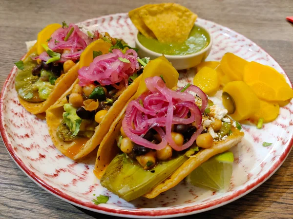 Süslü bir tabakta servis edilen Meksika tacoları ve quacamole 'lu nachos..