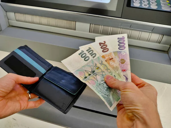 Birisi ATM 'den çekilen parayı cüzdanına koyuyor..