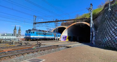Prag, Çek Cumhuriyeti: 17 Nisan 2022 - Elektrikli demiryolu ile tünelden çıkan mavi yolcu treni. Hava güneşli ve gökyüzü açık..