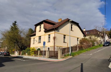 Prag, Çek Cumhuriyeti: 15 Nisan 2022 - Bulutlu bir günde iki caddenin kesiştiği noktada kırmızı çatılı ve tahta çitli tipik Çek aile evi.