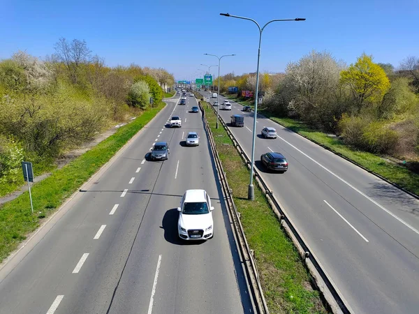 Prague, Czech Republic: April 23, 2022 - Cars on the straight highway with green stripe and street lamps in between the two main lines.