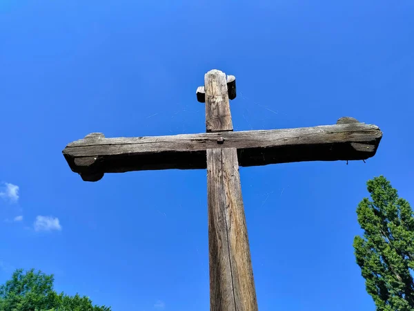 Old wooden cross on the background of the blue sky. The cross is a relic from middle ages preserved until today.