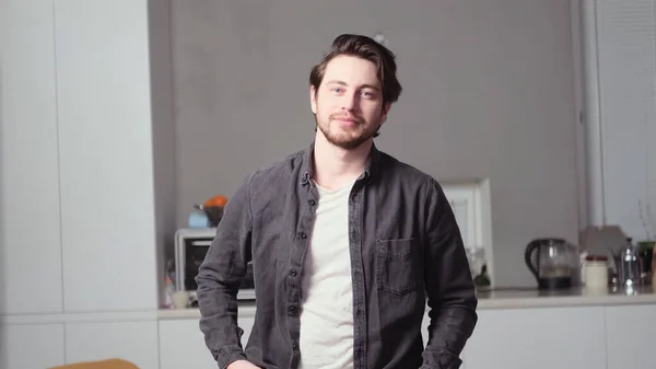 Siyah saçlı bir adam poz veriyor.