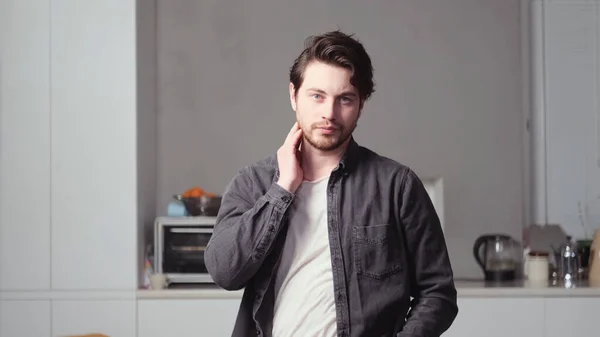 Siyah saçlı bir adam poz veriyor.