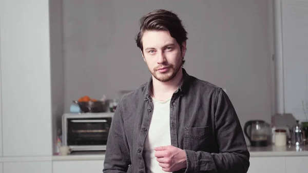 Siyah saçlı bir adam poz veriyor.