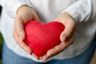 Kalbi tutan kadın elleri var. Aşk ve sağlık hizmeti kavramı. Seçici odaklanma. Yakın çekim görünümü.