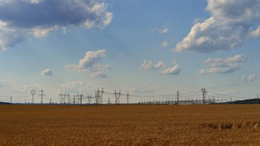 Yüksek voltajlı sütunlar. Mavi gökyüzü, bulutlar ve güneş doğada. Teknoloji ve endüstri kavramı. Artan elektrik ve enerji fiyatları - Rusya ile Ukrayna arasındaki savaşın yol açtığı enerji krizi. 