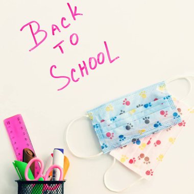 Okula dönelim. Okul gereçleri ve maskelerle dolu beyaz bir tahtaya yazılmış. Solunum cihazlarıyla..