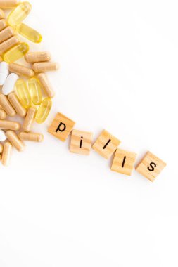 Farklı hapların beyaz arka planında tahta küplere kazınmış yazıtlar.