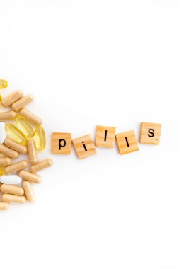 Farklı hapların beyaz arka planında tahta küplere kazınmış yazıtlar.