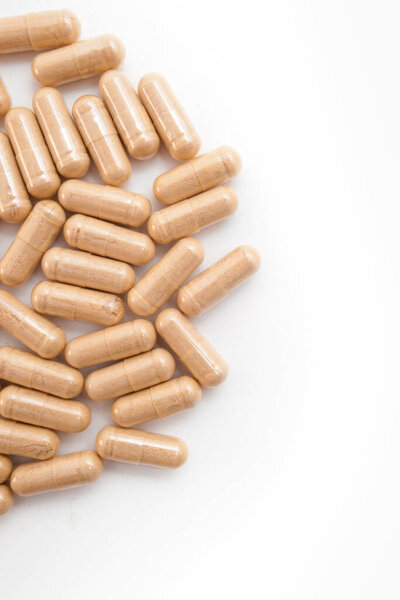Коричневые капсулы таблетки на белом изолированном фоне