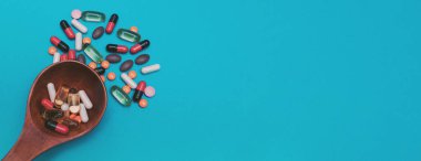 mavi panorama arka planında tahta kaşıkta çok renkli haplar.