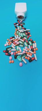 Panorama mavi arka planda kavanozdan düşen çok renkli haplar.