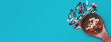 mavi panorama arka planında tahta kaşıkta çok renkli haplar.