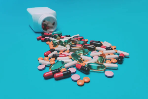 Többszínű Tabletták Kiesnek Egy Tégelyből Kék Alapon — Stock Fotó