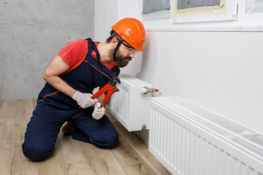 Turuncu kasklı bir işçi eve radyatör yerleştirir.