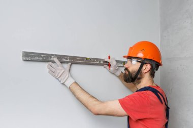 Turuncu kasklı bir işçi su seviyesiyle duvarları kontrol edecek.