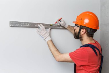 Turuncu kasklı bir işçi su seviyesiyle duvarları kontrol edecek.