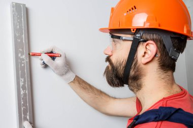 Turuncu kasklı bir işçi su seviyesiyle duvarları kontrol edecek.