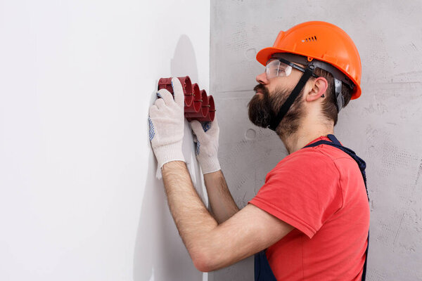 electrician in helmet installs sockets