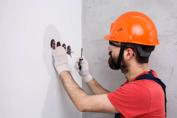 electrician in helmet installs sockets