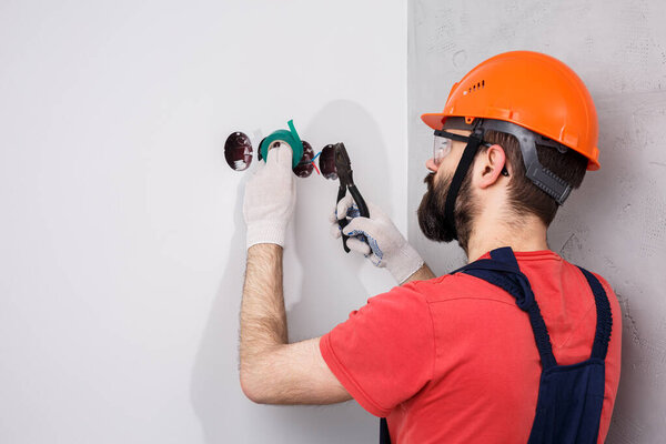 electrician in helmet installs sockets