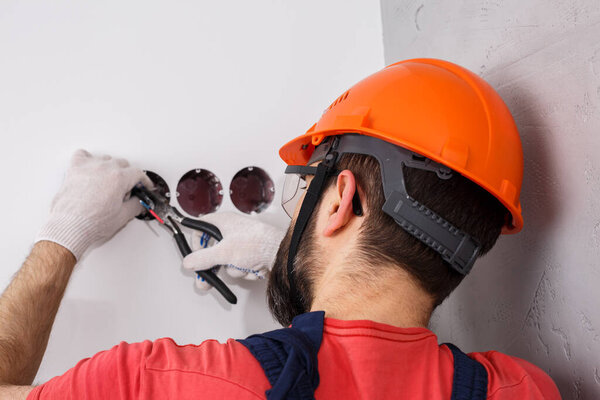 electrician in helmet installs sockets