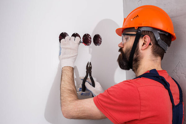 electrician in helmet installs sockets
