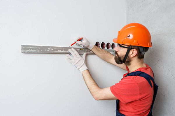 a worker in an orange helmet will check the walls with a water level