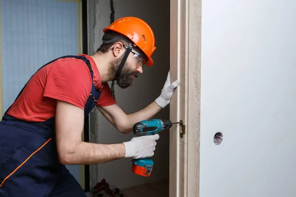 Travailleur Avec Une Perceuse Dans Casque Orange Installe Une Porte — Photo