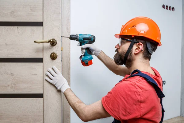 Travailleur Avec Une Perceuse Dans Casque Orange Installe Une Porte — Photo