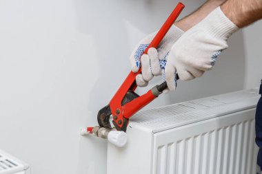 Turuncu kasklı bir işçi eve radyatör yerleştirir.