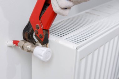 Turuncu kasklı bir işçi eve radyatör yerleştirir.