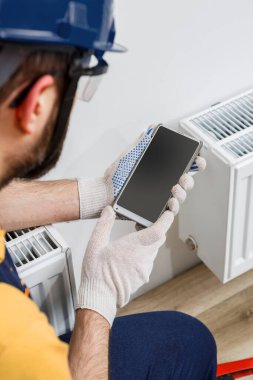 Turuncu kasklı bir işçi eve radyatör yerleştirir.