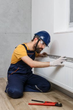 Turuncu kasklı bir işçi eve radyatör yerleştirir.