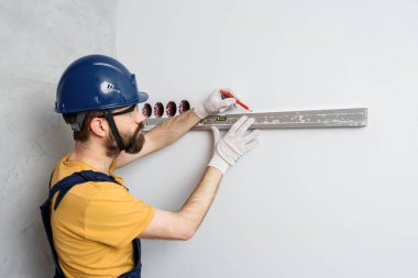 Turuncu kasklı bir işçi su seviyesiyle duvarları kontrol edecek.