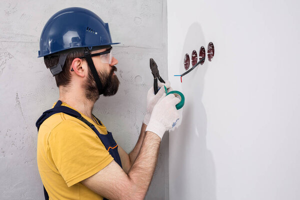 electrician in helmet installs sockets